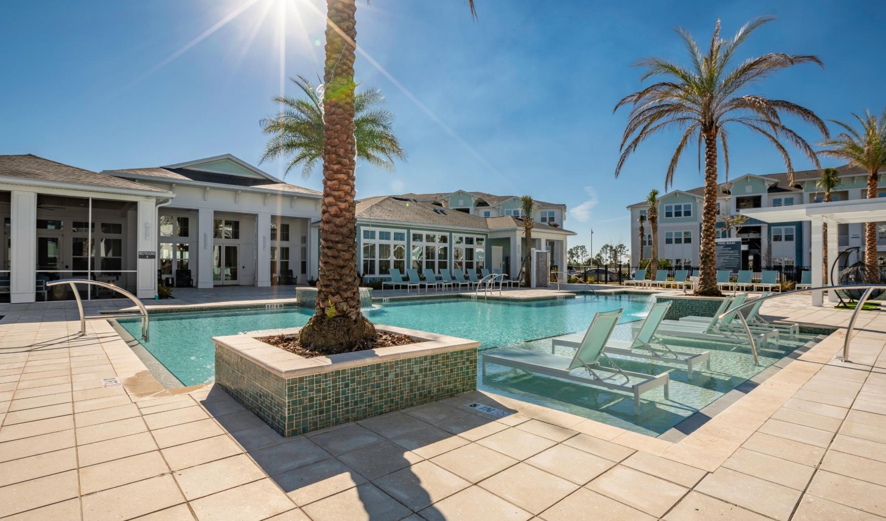 a pool with palm trees and a building in the background